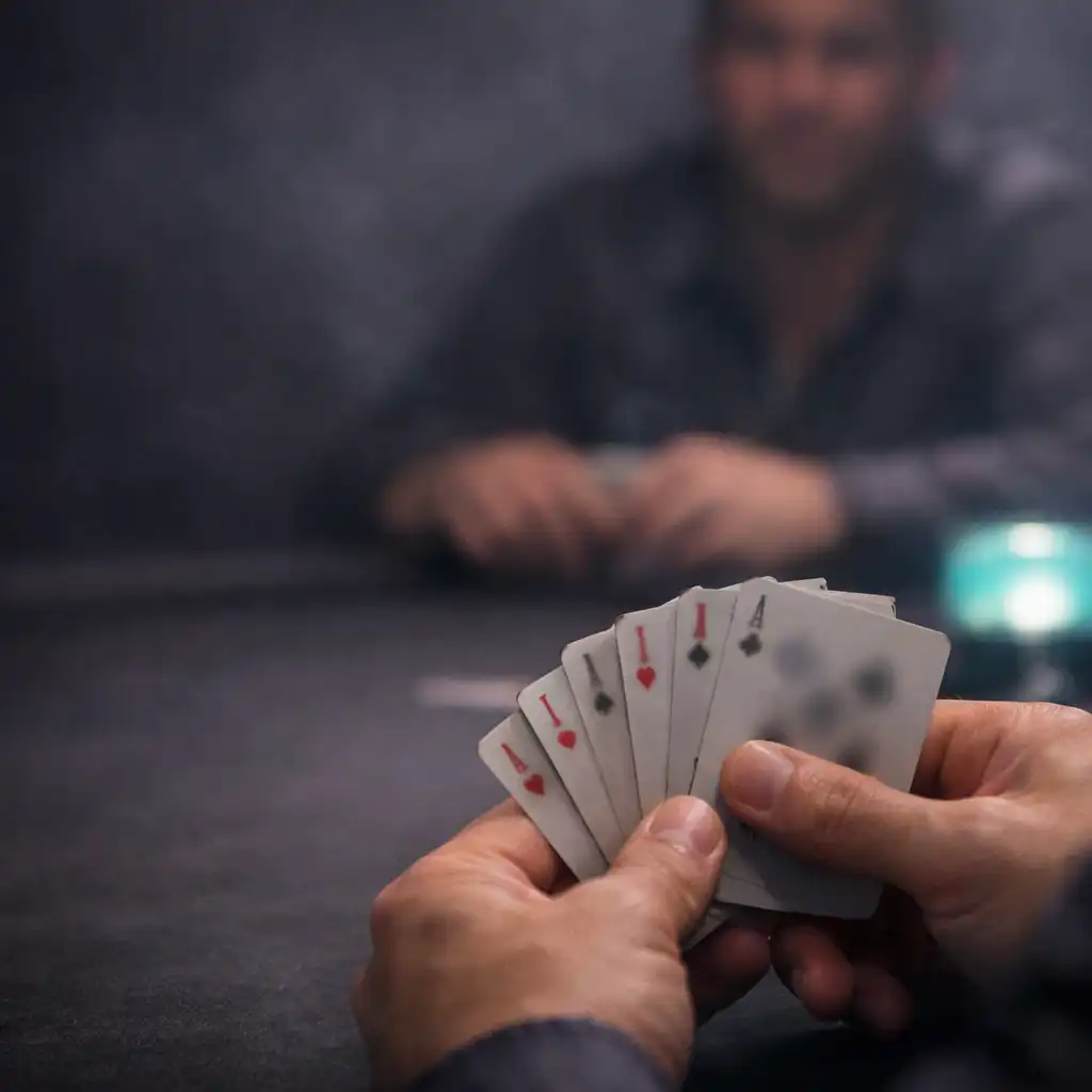 Hands holding real playing cards across a physical poker table